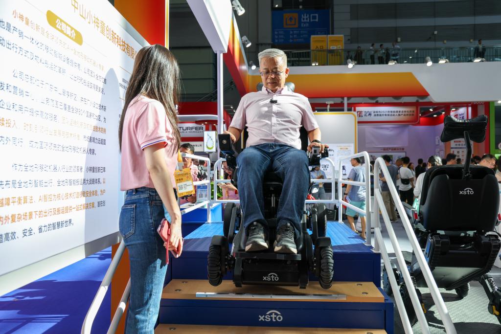 2025年9月12日,在2025深圳国际智慧养老产业博览会上,观众在展会现场体验一款可以上下楼梯的智能出行机器人。新华社记者 梁旭 摄