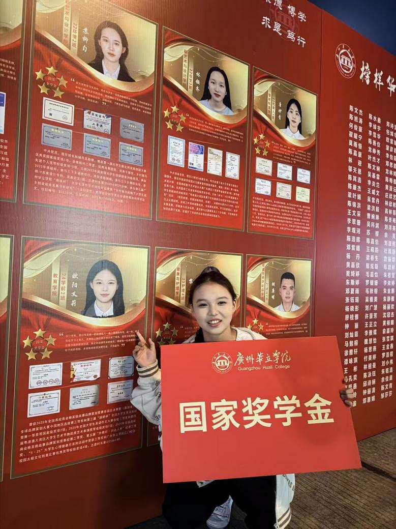正面形象照-欧阳义莉在学校的榜样人物展示墙前,手持国家奖学金的展示牌