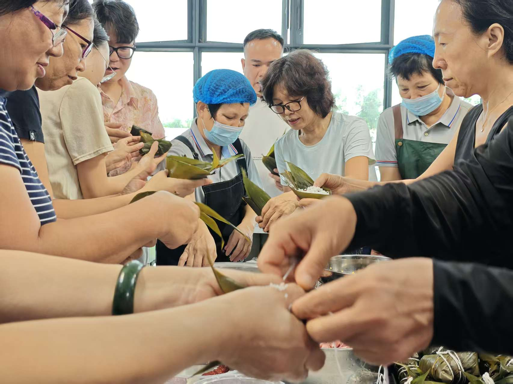 图3：老师们在教工饭堂阿姨的指导下学习包粽子